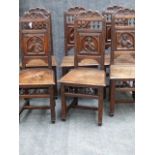 A SET OF SIX ANTIQUE CARVED OAK CONTINENTAL CHAIRS WITH SOLID SEATS, ELABORATE FIGURAL BACK PANELS