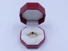 AN 9ct. SAPPHIRE AND DIAMOND TWO COLOUR RING. THE CENTRE SAPPHIRE IS A BLUE CABOCHON IN A BEZEL