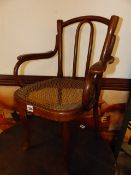 A VINTAGE THONET BENTWOOD CHILD'S ARMCHAIR WITH CANE SEAT, STAMPED THONET.
