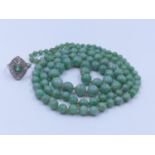An 84cm (33") CONTINUOUS GRADUATED AND KNOTTED STRAND OF GREEN JADE BEADS. WEIGHT 57 GRAMS
