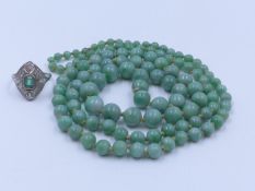 An 84cm (33") CONTINUOUS GRADUATED AND KNOTTED STRAND OF GREEN JADE BEADS. WEIGHT 57 GRAMS