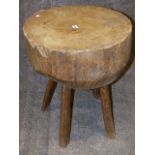 AN ANTIQUE RUSTIC PINE CHOPPING BLOCK ON FOUR SPLAYED SUPPORTS. DIA.52cms, H.69cms.