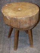 AN ANTIQUE RUSTIC PINE CHOPPING BLOCK ON FOUR SPLAYED SUPPORTS. DIA.52cms, H.69cms.