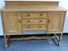 A HEAL'S PALE OAK EARLY 20th.C.SIDEBOARD WITH THREE CENTRAL DRAWERS FLANKED BY PANEL DOOR CUPBOARDS.