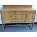 A HEAL'S PALE OAK EARLY 20th.C.SIDEBOARD WITH THREE CENTRAL DRAWERS FLANKED BY PANEL DOOR CUPBOARDS.