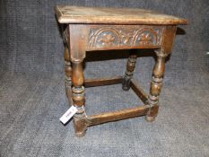 A CARVED OAK JOINT STOOL WITH MOULDED EDGE TOP AND BOX STRETCHED TURNED LEGS.