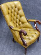 A CARVED MAHOGANY VICTORIAN STYLE ARMCHAIR WITH BUTTONED OLIVE GREEN LEATHER ON BRASS CASTORS.