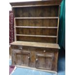 AN ANTIQUE COUNTRY PINE DRESSER WITH PLATE RACK ABOVE TWO DRAWERS AND TWO PANELLED DOORS, POSSIBLY