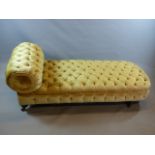 A VICTORIAN CHAISE WITH BUTTONED CHAMPAGNE PLUSH COVER, SHORT EBONISED TURNED LEGS WITH GILT BANDING