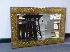 A BRASS ARTS AND CRAFTS MIRROR WITH BEVELLED PLATE AND SPIRAL TWIST DECORATED FRAME. 57x84cms.