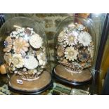 A PAIR OF VICTORIAN SHELL WORK FLORAL DISPLAYS WITHIN GLASS DOMES ON EBONIZED OVAL BASES. H.39cm.