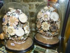 A PAIR OF VICTORIAN SHELL WORK FLORAL DISPLAYS WITHIN GLASS DOMES ON EBONIZED OVAL BASES. H.39cm.