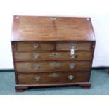 A MAHOGANY GEORGIAN SLANT FRONT BUREAU WITH FITTED INTERIOR ABOVE FIVE DRAWERS STANDING ON BRACKET