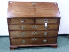 A MAHOGANY GEORGIAN SLANT FRONT BUREAU WITH FITTED INTERIOR ABOVE FIVE DRAWERS STANDING ON BRACKET