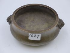 A HEAVY CHINESE BRONZE CENSER WITH MASK HANDLES AND IMPRESSED MARKS TO BASE. D.16cms