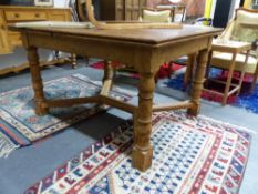 AN EARLY 20th.C. PALE OAK DRAW LEAF DINING TABLE WITH RING TURNED LEGS JOINED BY SHAPED CROSS