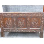 AN EARLY CARVED OAK COFFER WITH THREE PANEL FRONT AND HIGH STILE FEET. W.138cms x D.58cms x H.