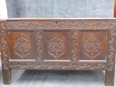 AN EARLY CARVED OAK COFFER WITH THREE PANEL FRONT AND HIGH STILE FEET. W.138cms x D.58cms x H.