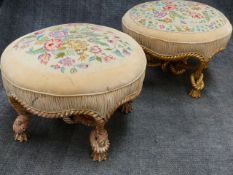 TWO SIMILAR FRENCH CARVED GILTWOOD LARGE ROUND STOOLS WITH FLORAL NEEDLEPOINT SEATS. ELABORATE