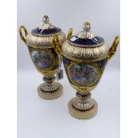 A PAIR OF BERLIN PORCELAIN TWO HANDLED LIDDED PEDESTAL VASES WITH HAND PAINTED GENRE SCENES. H.
