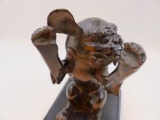 A JAPANESE BRONZE FIGURE OF A SEATED FOO LION MOUNTED ON A LATER EBONISED BASE. H. OVERALL 21cms.