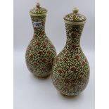 A PAIR OF PERSIAN POTTERY BOTTLE FORM COVERED VASES WITH OVERALL SCROLLING DECORATION. H.33cms.