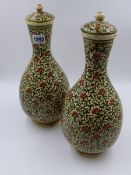 A PAIR OF PERSIAN POTTERY BOTTLE FORM COVERED VASES WITH OVERALL SCROLLING DECORATION. H.33cms.