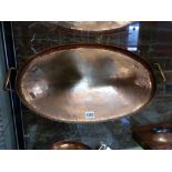 A HUGH WALLIS ARTS AND CRAFTS COPPER OVAL TWIN HANDLED TRAY WITH GADROON RIM. W.62cms.
