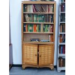 AN INTERESTING MID CENTURY SATINBIRCH BOOKCASE CABINET WITH BRASS MOUNTED FEET.