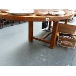 A LARGE OAK EXTENDING DINING TABLE ON REFECTORY TYPE BASE.