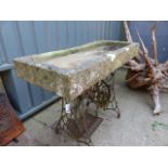 A STONE TROUGH ON CAST IRON BASE.