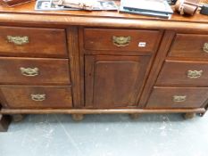 A VICTORIAN DRESSER BASE WITH CENTRAL CUPBOARD AND SIX DRAWERS.