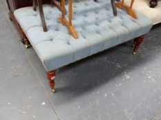 A LARGE BUTTON UPHOLSTERED STOOL ON TURNED LEGS WITH BRASS CASTERS.