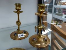 A PAIR OF ARTS AND CRAFTS BRASS CANDLESTICKS INSET WITH CABOCHON STONES.