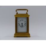 A MINIATURE BRASS CASED CARRIAGE CLOCK WITH WHITE ENAMEL DIAL. H.9cms (INCLUDING HANDLE)