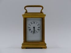 A MINIATURE BRASS CASED CARRIAGE CLOCK WITH WHITE ENAMEL DIAL. H.9cms (INCLUDING HANDLE)