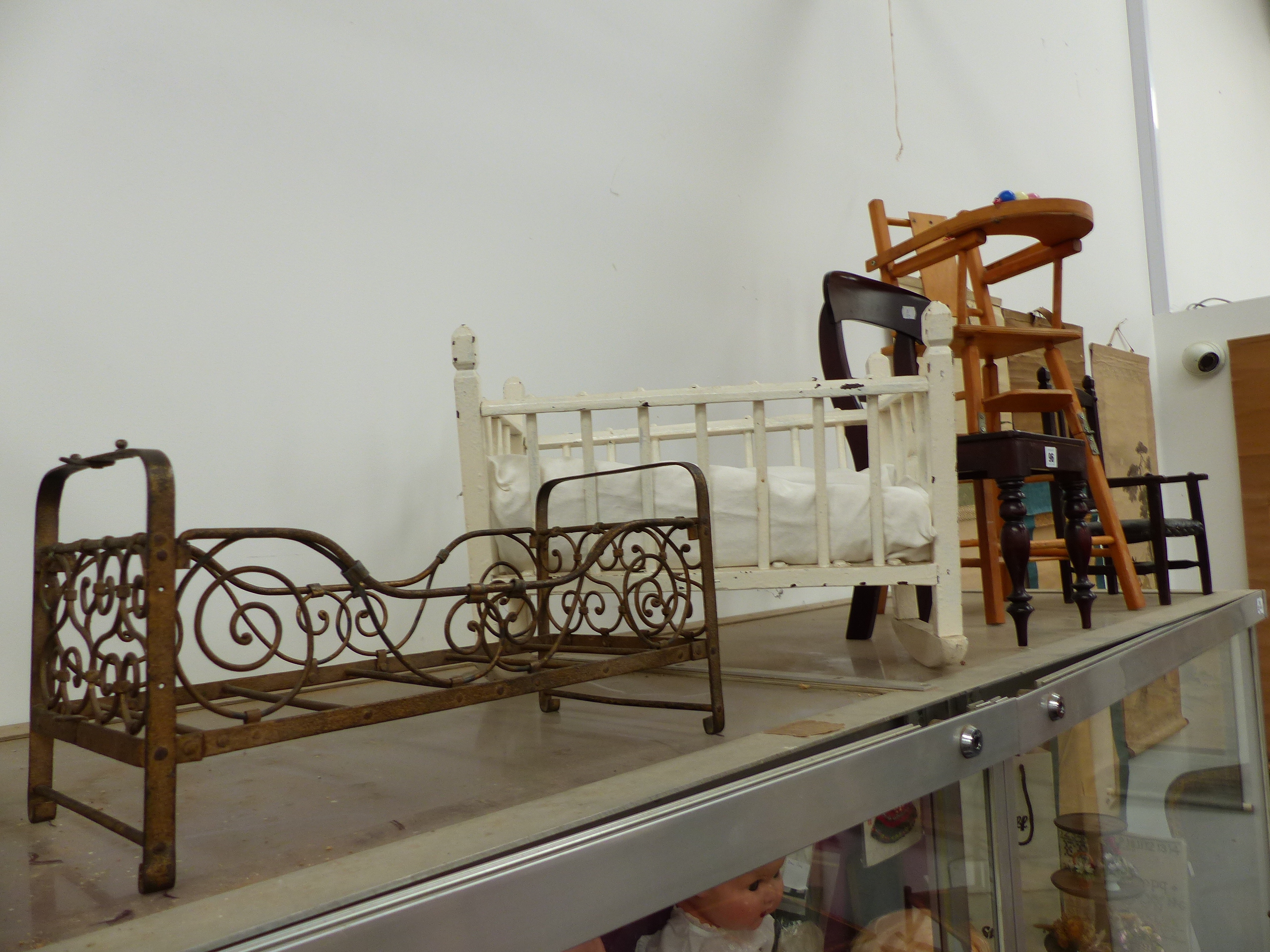 AN ANTIQUE IRON DOLL'S BED, THREE DOLL'S CHAIRS, A ROCKING CRADLE AND A SMALL PAINTED BIRDCAGE