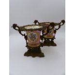 A PAIR OF SEVRES STYLE ORMOLU MOUNTED CACHE POTS. WITH FLORAL PANELS AND MONOGRAMS ON A PINK GROUND.