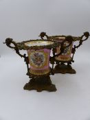 A PAIR OF SEVRES STYLE ORMOLU MOUNTED CACHE POTS. WITH FLORAL PANELS AND MONOGRAMS ON A PINK GROUND.