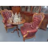 A PAIR OF CARVED VICTORIAN STYLE LIBRARY ARMCHAIRS COVERED IN BUTTONED RED LEATHER.