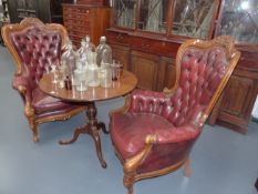 A PAIR OF CARVED VICTORIAN STYLE LIBRARY ARMCHAIRS COVERED IN BUTTONED RED LEATHER.