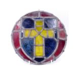 AN ANTIQUE STAINED GLASS ROUNDEL OF A CROSS WITHIN A SHIELD. D.24cms.