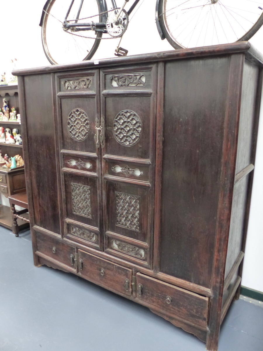 AN IMPRESSIVE CHINESE CARVED CABINET WITH TWO PIERCED PANEL DOORS ABOVE THREE BASE DRAWERS. H.166