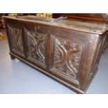 AN 18th.C.OAK COFFER WITH THREE PANEL FRONT INCORPORATING EARLIER CARVED PANELS. W.141cms.