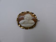 AN OVAL CARVED CAMEO BROOCH DEPICTING A GAZING CHERUB MOUNTED IN PRECIOUS YELLOW METAL TESTED AS