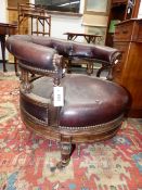 AN UNUSUAL VICTORIAN CARVED ROSEWOOD REVOLVING LOW SALON ARMCHAIR IN NAILED BROWN LEATHER,