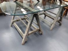 A PAIR OF ANTIQUE DECORATOR'S TRESTLES NOW MOUNTED WITH PLATE GLASS BEVEL EDGE TOP.