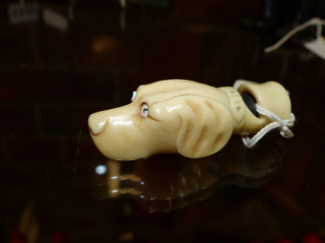 AN ANTIQUE CARVED IVORY WHISTLE IN THE FORM OF A DOG'S HEAD. W.6.5cms.