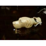 AN ANTIQUE CARVED IVORY WHISTLE IN THE FORM OF A DOG'S HEAD. W.6.5cms.