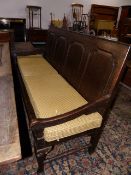 A GEO.III.COUNTRY OAK HALL SETTLE WITH PANEL BACK STANDING ON STOUT CABRIOLE LEGS. W.182cms.